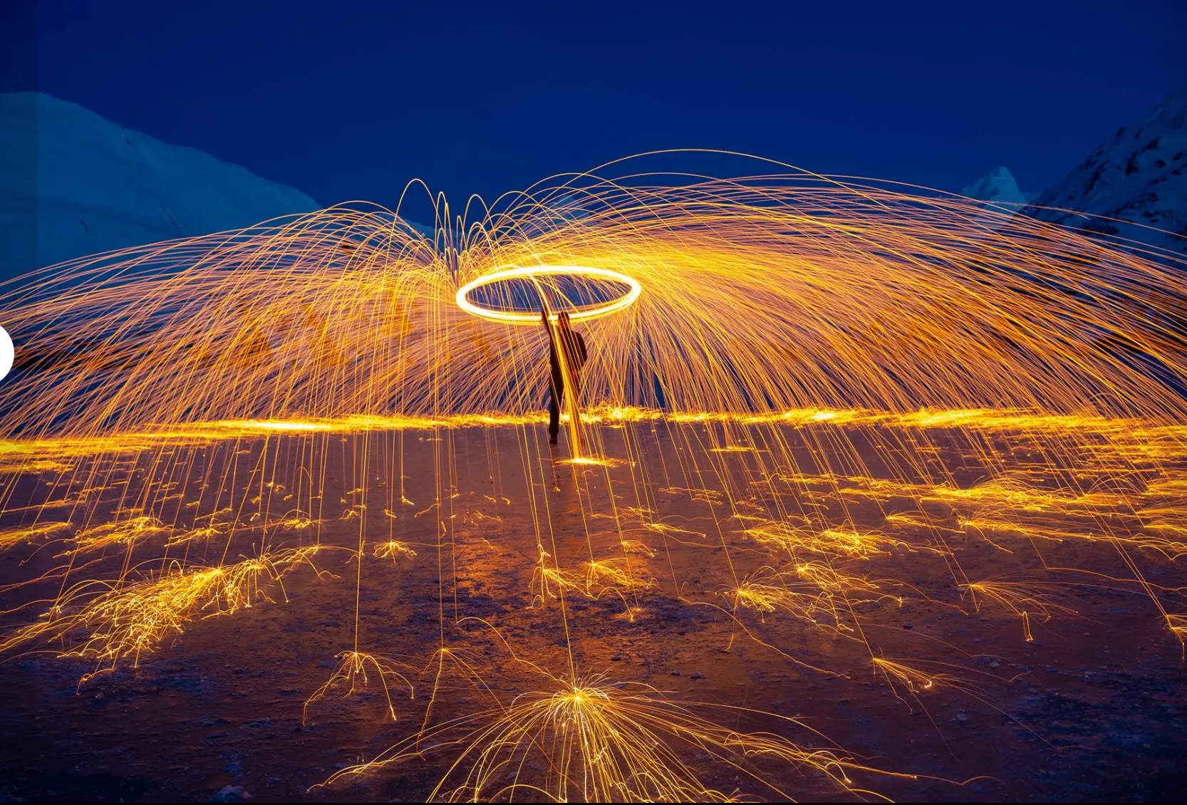 Steel wool sparks arcing over an Alaska mountain landscape at twilight